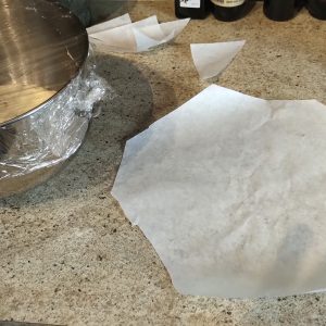 The second raising is finished, prepared a square of baking paper and cut the corners to facilitate the casserole.