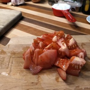 Pendant ce temps, ciseler l&rsquo;oignon et l&rsquo;ail. Couper la tomate en dés.