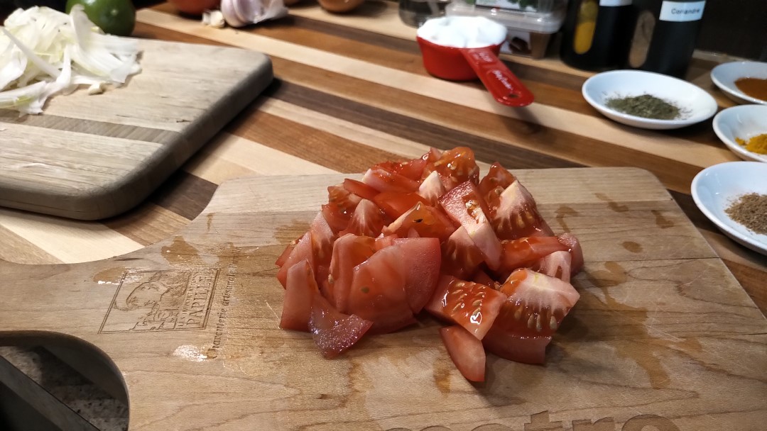 Pendant ce temps, ciseler l'oignon et l'ail. Couper la tomate en dés.